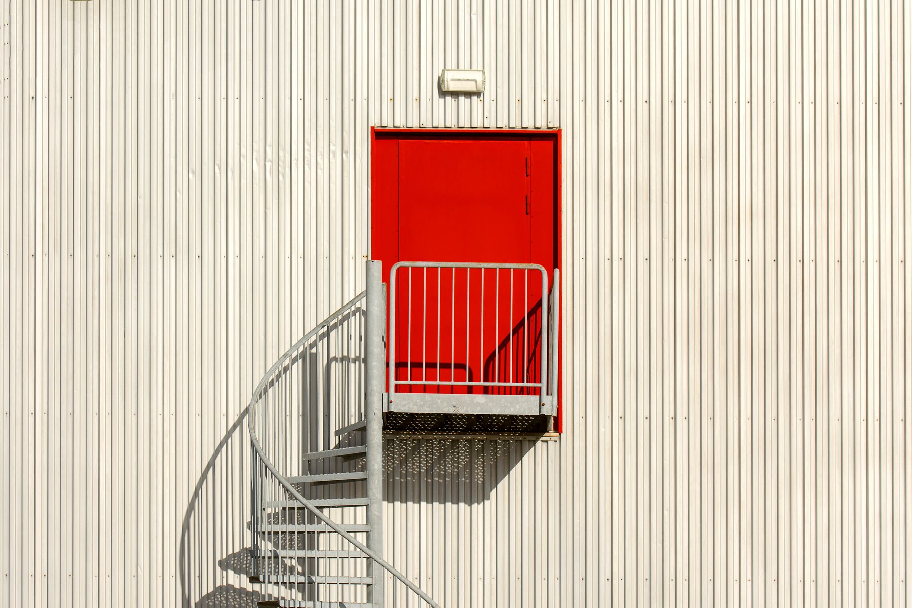 Moderne Fassade mit roter Tür und Außentreppe als visuelle Illustration